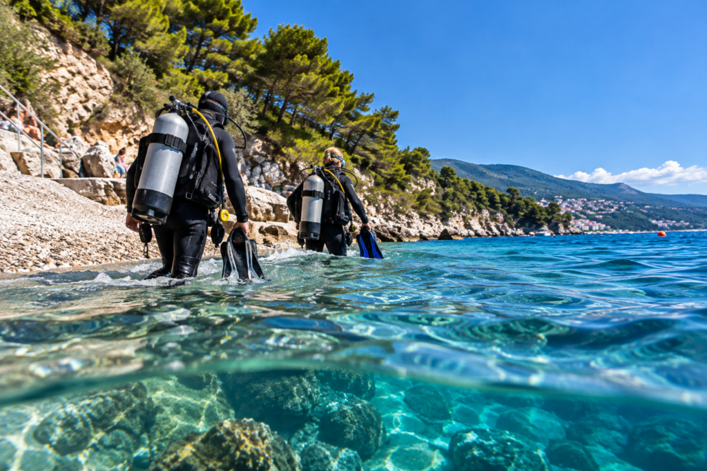 Tauchgänge in Rabac am Hausriff Girandella: Zwei Taucher steigen ins türkisfarbene Meer ein.