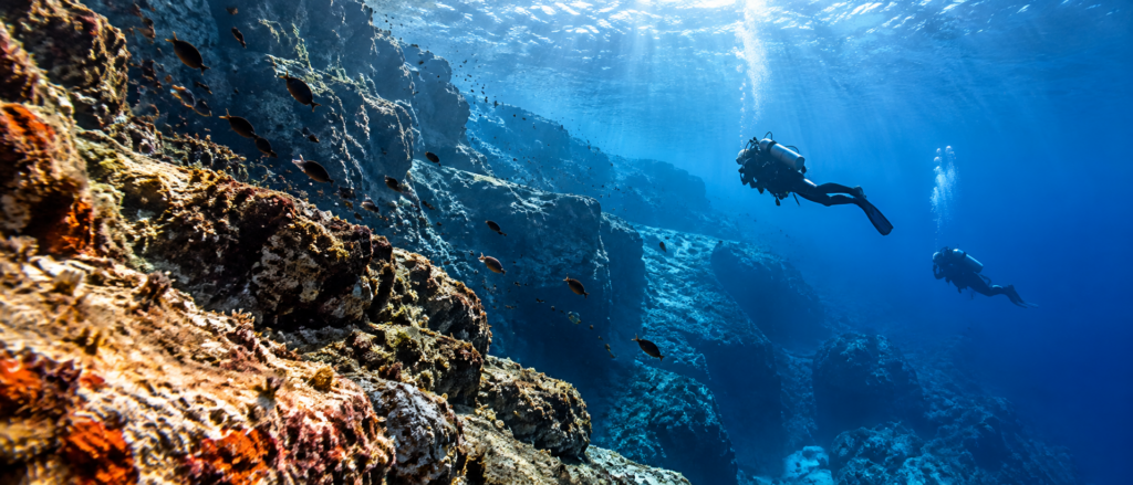 Divers exploring rocky underwater landscapes at dive sites in Rabac, Croatia